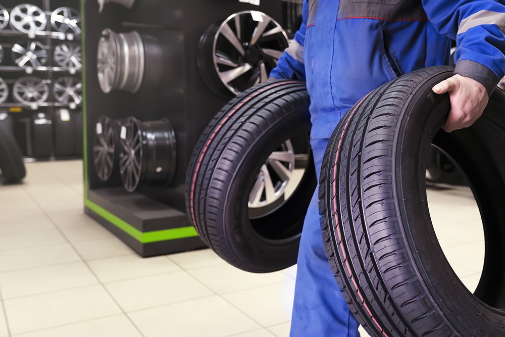 Mechanic carrying vehicle tires. Photo ID 237320416 © Vladimir Razgulyaev | Dreamstime.com